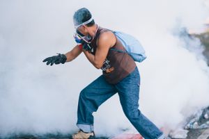 A protester running away from a tear gas canister during a stand-off between anti-Government protesters and police at Government House in Bangkok.