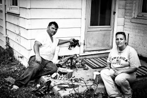 A couple remove parts from a television set in the hope they can sell the metal for cash.