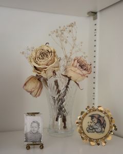 A small photo of Gramps when he was a child, next to dried roses and a Hummel print.