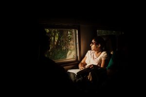 A commuter on the early morning train from Colombo to Kandy is illuminated by the sun shining through a window.