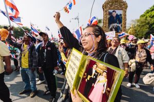 An Anti-Government protester carrying a portrait of the King and Queen of Thailand celebrating at a rally aimed at unseating the Prime Minister of Thailand. Anti-Government protesters led by the People's Democratic Reform Committee's (PDRC) marched towards Government House in Bangkok on Monday 9th December, 2013, where they heard the news that Prime Minister, Yingluck Shinawatra, brother of former